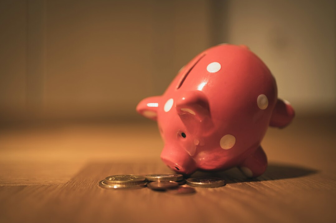 person putting coin in piggy bank